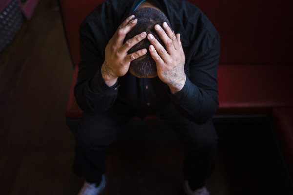Man sitting on seat, looking down with head in his hands