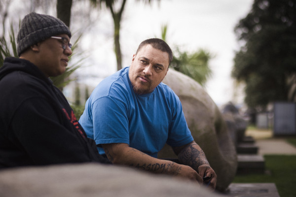 Two men sitting on a bench outside 