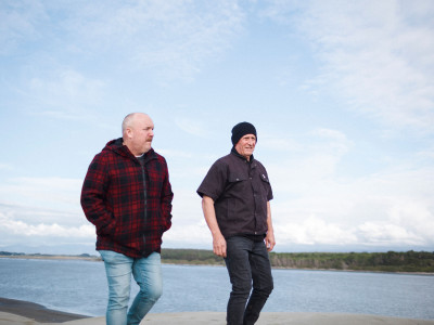Two men walking along a beach together
