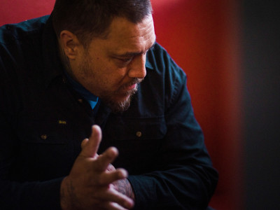 Image of man sitting down, looking away from camera, looking pensive