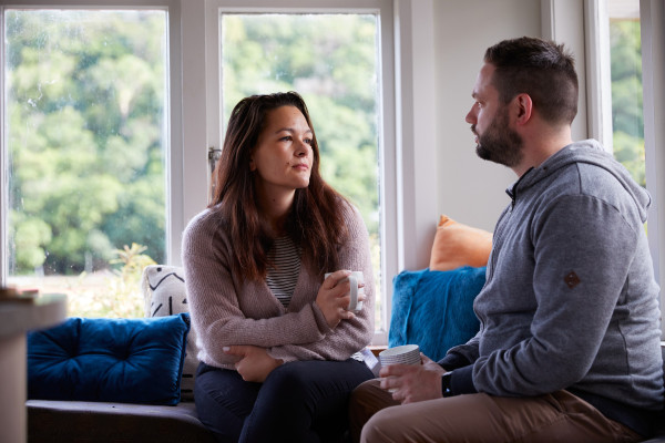 Man and woman sitting facing each other holding cups of tea